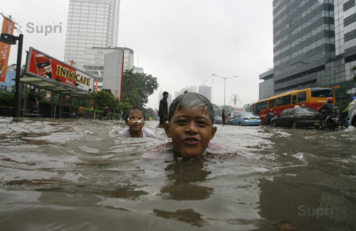 Indonesian children play in a flooded central Jakarta business district