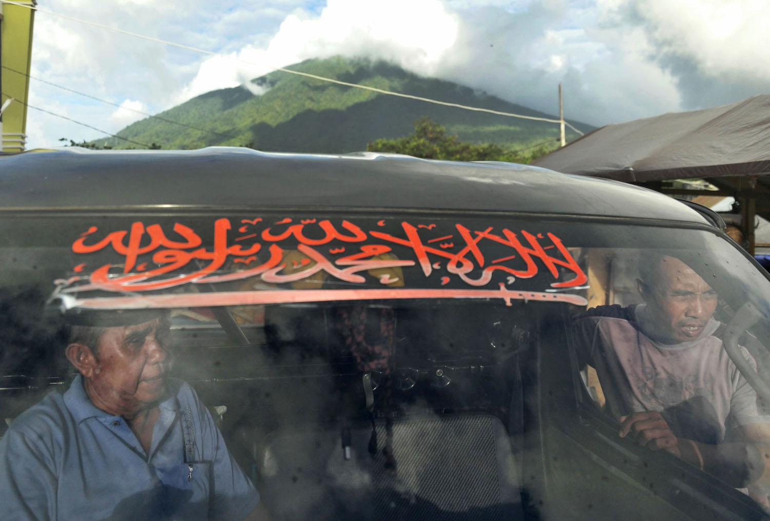 Stiker bertulisan dua kalimat syahadat ditempel di kaca depan sebuah mobil.