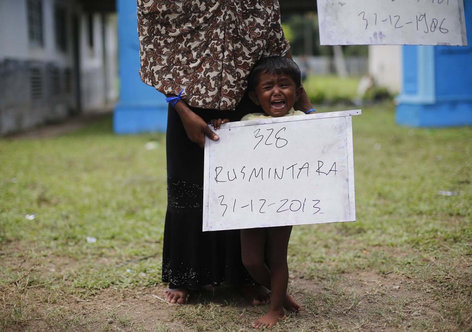 Rohingya migrant mother, who recently arrived in Indonesia by boat, holds a placard of her child during photograph for immigration identification inside a temporary compound for refugees in Aceh Timur regency