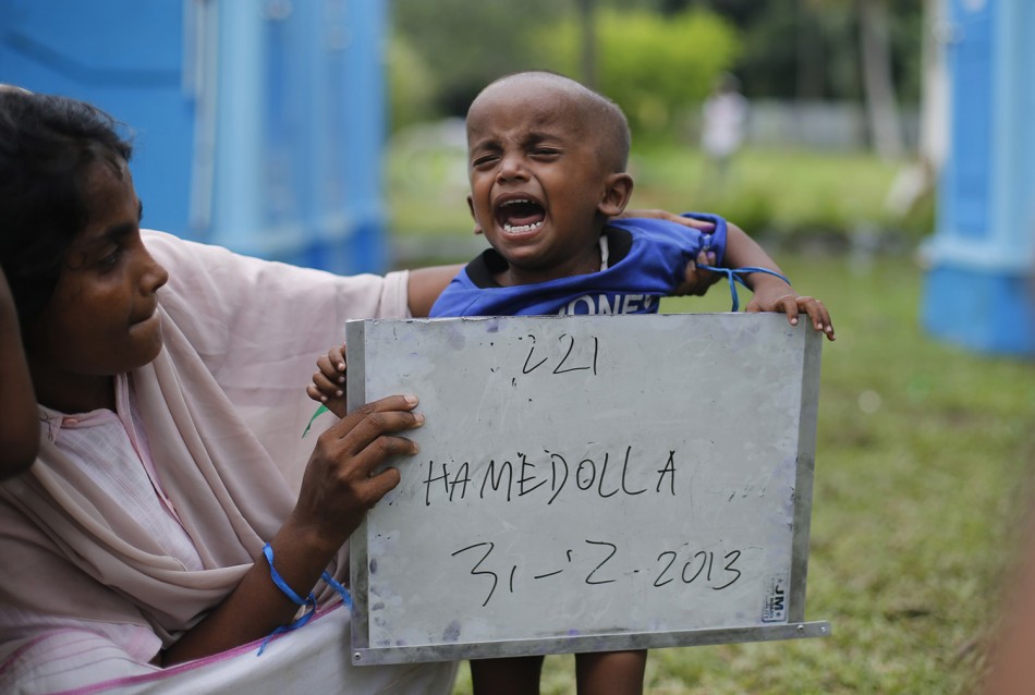 Rohingya migrant mother, who recently arrived in Indonesia by boat, holds her child placard while posing for photographs for immigration identification purposes inside a temporary compound for refugees in Aceh Timur regency