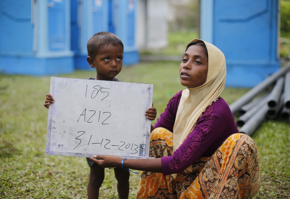 Rohingya migrant mother (R), who recently arrived in Indonesia by boat, holds her child placard while posing for photographs for immigration identification purposes inside a temporary compound for refugees in Aceh Timur regency